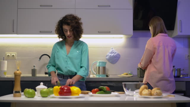 Two-female-friends-cooking-salad-at-home-in-the-kitchen,-leisure,-togetherness