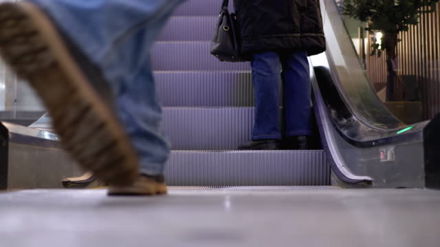 Legs-of-People-Moving-on-a-Escalator-Lift-in-the-Mall.-Shopper-es-Feet-auf-Rolltreppe-im-Einkaufszentrum