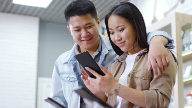 Asian-Couple-Testing-Smartphone-and-Smiling