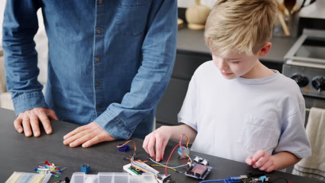 Enkel-mit-Großvater-montage-elektronische-Komponenten,-um-Roboter-zusammen-zu-Hause-zu-bauen