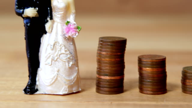 Mini-Brautpaar-stehen-neben-Stapel-von-Münzen