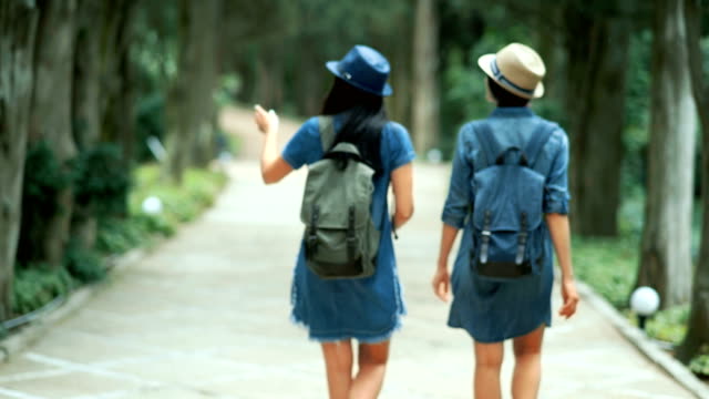 Two-tourist-women-with-backpacks-walking-in-the-park