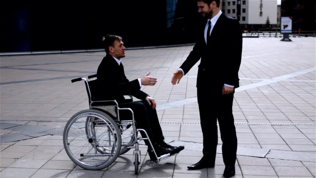 Happy-boss-shaking-hands-with-disabled-colleague-outdoor
