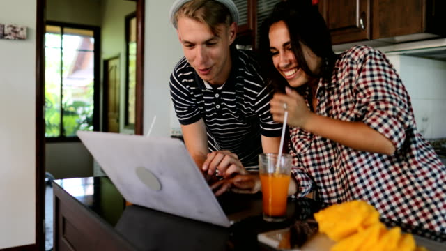 Couple-Use-Laptop-Computer,-Young-Woman-And-Man-In-Kitchen-Studio-Talking-Modern-House-Interior