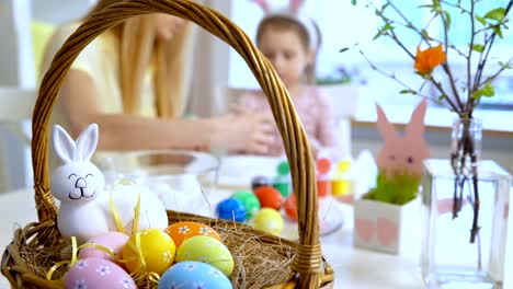 Happy-Easter!-Mother-and-her-little-daughter-wearing-funny-rabbit-ears-coloring-easter-eggs