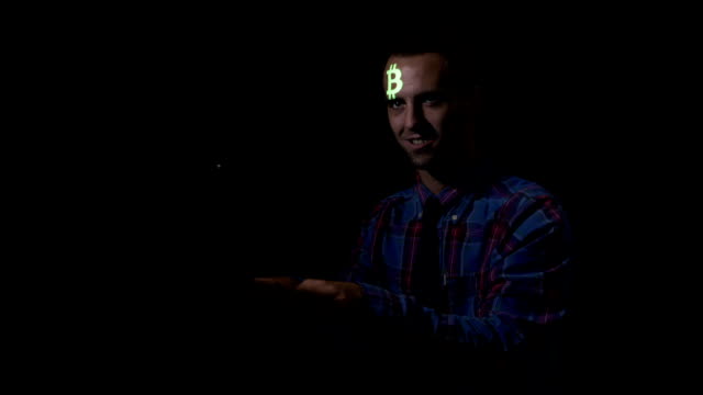 Male-hacker-sitting-in-a-dark-room-in-front-the-computer-and-attacking-corporate-servers-to-steal-bitcoin-currency