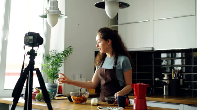 Attraktives-Mädchen-Aufnahme-video-Essen-Vlog-über-gesundes-Kochen-auf-Digitalkamera-in-der-Küche-zu-Hause.-Vlogs-und-social-Media-Konzept