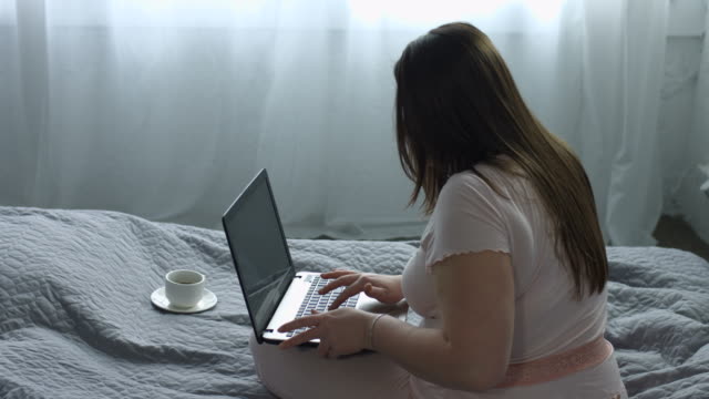 Mujer-atractiva,-escribiendo-en-la-laptop-en-la-cama