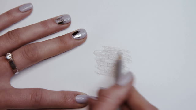 Female-hand-shades-with-pencil-on-paper-and-appears-image-of-bitcoin