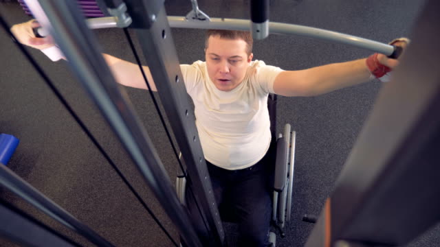Sportler-im-Rollstuhl-stärkt-die-Rückenmuskulatur-in-einer-Turnhalle.