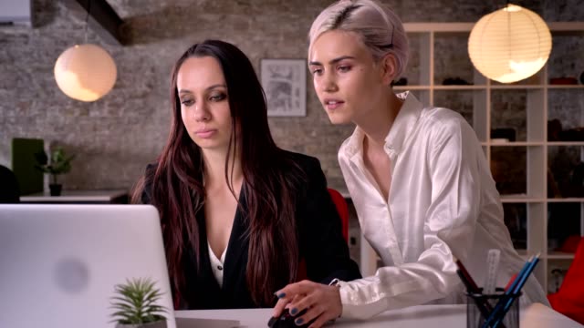 Zwei-junge-hübsche-Lesben-arbeiten-in-modernen-Büros,-Frau-mit-Frau,-berühren-ihre-Hand,-verführerisch-und-sexy-flirten