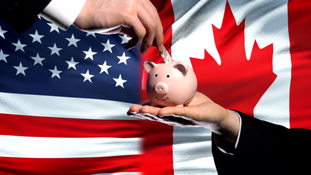US-investment-in-Canada,-hand-putting-money-in-piggybank-on-flag-background