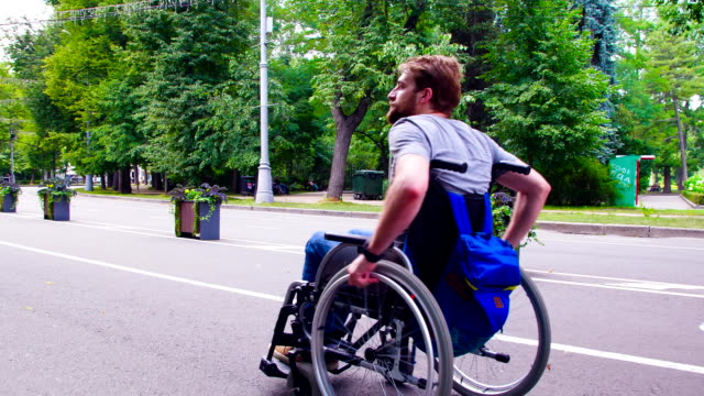Young-disable-man-walking-in-the-park-in-wheelchair