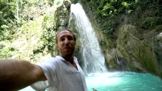 Junger-Mann-unter-Selfie-Porträt-mit-einem-wunderschönen-Wasserfall