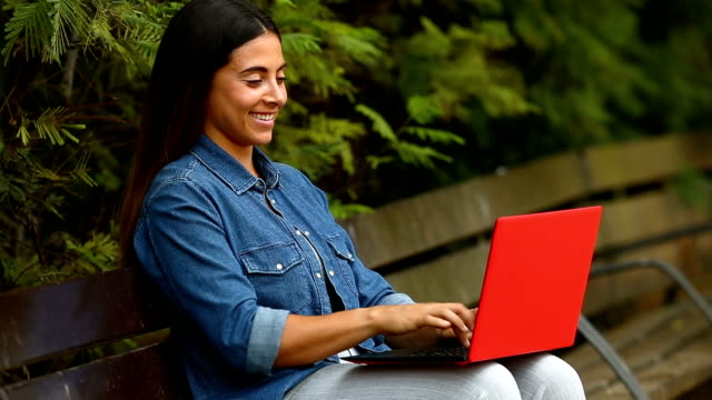 Frau-Chating-online-mit-einem-Laptop-in-einem-park