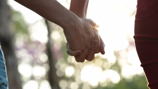 Close-up-of-hands-joining-together-with-sunlight-flare-in-the-background2.-Beautiful-romantic-moment-between-two-lovers