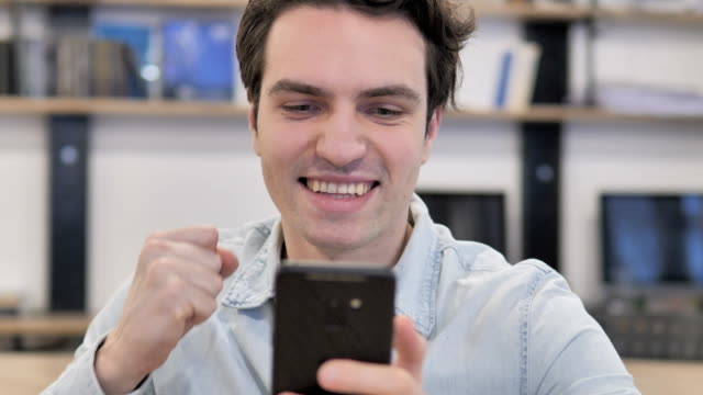 Portrait-of-Creative-Man-Excited-for-Success-while-Using-Smartphon