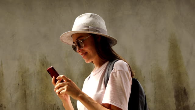 Smiling-female-traveler-using-smartphone