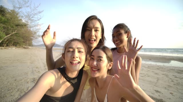 Group-of-young-hipster-friends-taking-selfies-on-smartphone-at-the-beach-in-summer-vacation.-People-with-travel,-holiday-and-party-concept.-Slow-motion