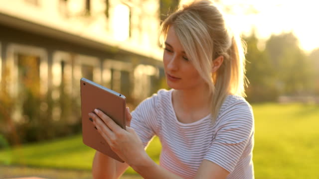 Young-female-student-using-tablet-computer-in-the-park.-Girl-doing-online-shopping-on-tablet-pc