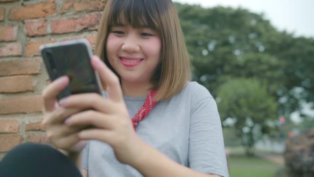 Reisende-asiatische-Frau,-die-Smartphone-nutzt,-prüft-soziale-Medien,-während-sie-sich-nach-einer-Urlaubsreise-in-Ayutthaya,-Thailand,-entspannen.