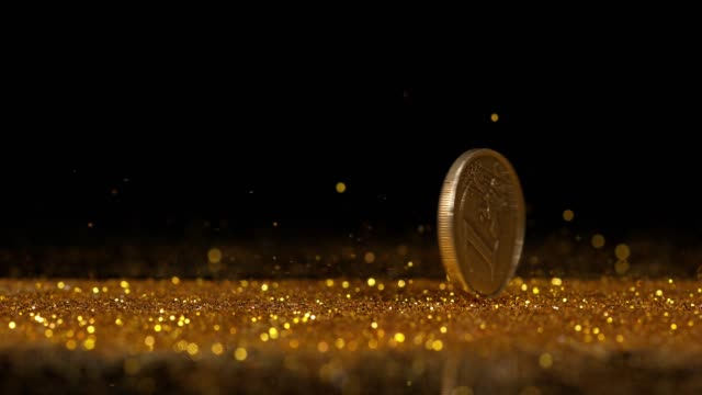 Münze-von-1-Euro-Rolling-auf-Goldpulver-gegen-schwarzen-Hintergrund,-Slow-motion-4K