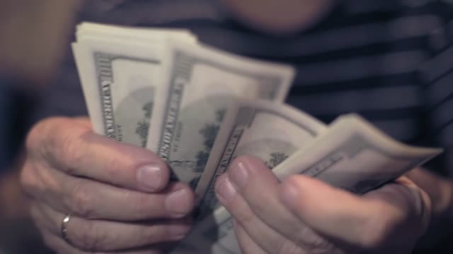 man-considers-cash-on-costs-,-male-hand-with-money-closeup,-planning-the-family-budget
