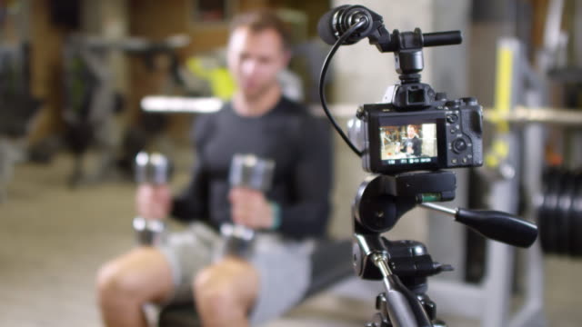 Fitness-Coach-Explaining-and-Showing-Side-Dumbbell-Raise-on-Camera