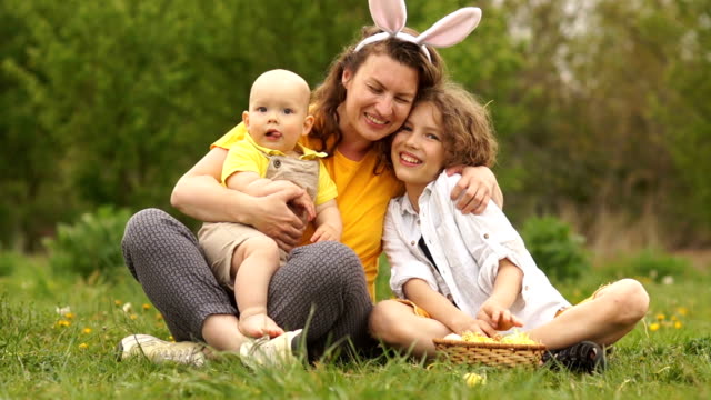Lovely-family-hugging-in-the-park-at-a-picnic.-Happy-Easter-family.-Mom-and-two-sons.-Mothers-Day