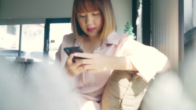 Mujer-freelance-de-negocios-asiática-usando-un-teléfono-inteligente-para-hablar,-leer-y-enviar-mensajes-de-texto-mientras-está-sentado-en-la-mesa-en-la-cafetería.-Estilo-de-vida-inteligente-mujeres-hermosas-trabajando-en-los-conceptos-de-cafetería.