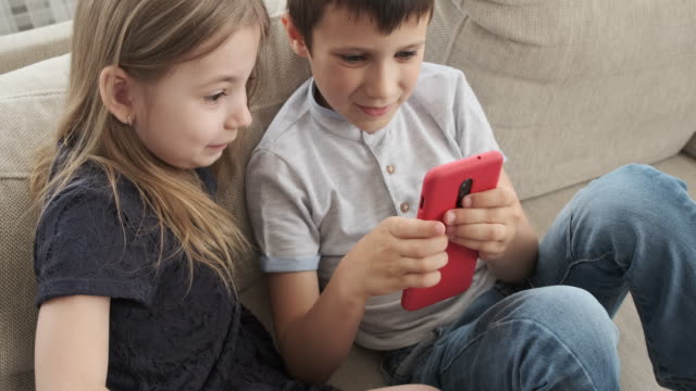 Niños-que-usan-el-teléfono-móvil-en-el-sofá