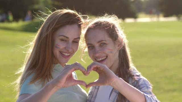 Portrait-of-smiling-lesbians-showing-hand-heart