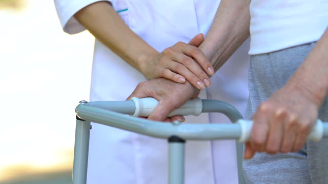 Fisioterapeuta-apoyando-a-personas-discapacitadas-y-motivando-a-moverse-sobre-los-caminantes