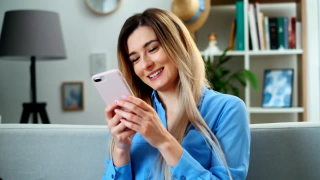 Portrait-of-girl-using-mobile-device-browsing-the-internet,-staying-connected-at-home-enjoying-modern-lifestyle.-Pretty-young-woman-using-smartphone-on-the-couch,-texting-while-relaxing