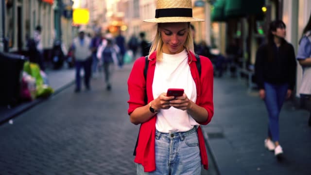 Positive-kaukasische-Frau-Tourist-chattet-über-Handy-mit-4G-Internet-im-Roaming-verbunden,-Millennial-weibliche-Typisierung-Textnachricht-auf-dem-Smartphone-auf-der-Straße