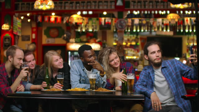 En-el-bar-o-restaurante-hombre-hispano-se-toma-selfie-de-sí-misma-y-sus-mejores-amigos.-Grupo-Hermosos-Jóvenes-en-Establecimiento-Elegante