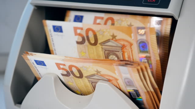 Billetes-naranjas-en-euros-contados-en-una-máquina.