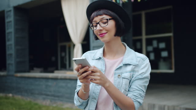 Fröhliche-Mädchen-mit-Smartphone-im-Freien-lächelnd-berührenden-Bildschirm-genießen-Gerät