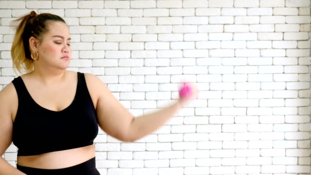large-build-young-woman-in-sportswear-exercising-with-dumbball-at-home