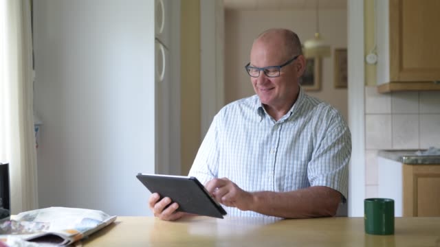 Glücklicher-Senior-Mann-mit-digitalen-Tablet-in-der-Nähe-des-Fensters