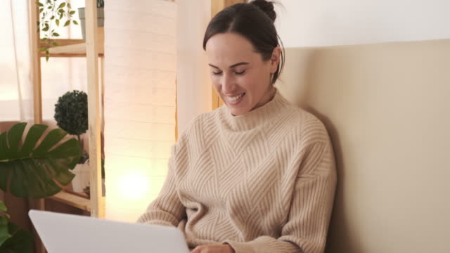 Mujer-feliz-usando-computadora-portátil-en-la-cama