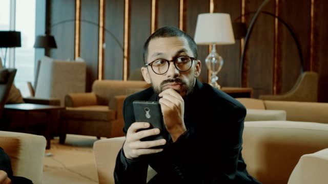 Retrato-de-la-etnia-árabe-hombre-guapo-usando-un-teléfono-inteligente-negro-en-la-reunión-de-negocios.-4K