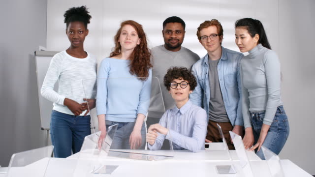 Fröhlicher-Lehrer-posiert-mit-multiethnischen-Schülern-in-futuristischem-Klassenzimmer