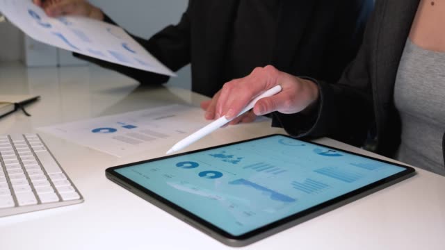 Geschäftsmann-und-Frau-arbeiten-auf-Tablet-Computer-und-analysieren-einen-Marketing-Bericht-auf-White-Desk