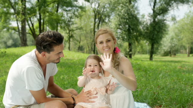 CLOSE-UP:-Cute-parents-with-beautiful-baby-girl-sitting-on-blanket-in-park