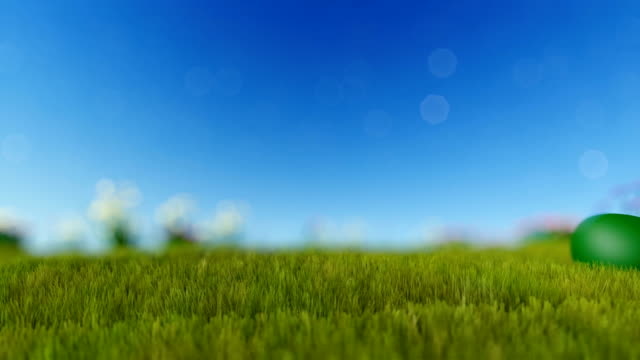 Easter-eggs-on-green-meadow-over-blue-blurry-sky,-panning