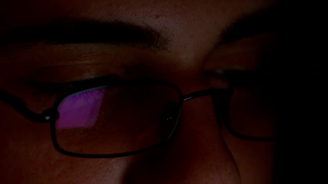 Closeup-of-teenager-eyes-wearing-glasses-and-browsing-internet-on-tablet-pc-in-a-dark-room