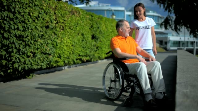 Mujer-amable-voluntaria-de-descanso-con-un-hombre-wheelchaired