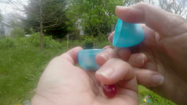 POV-of-a-hand-opening-up-a-plastic-Easter-egg-with-jelly-beans-inside