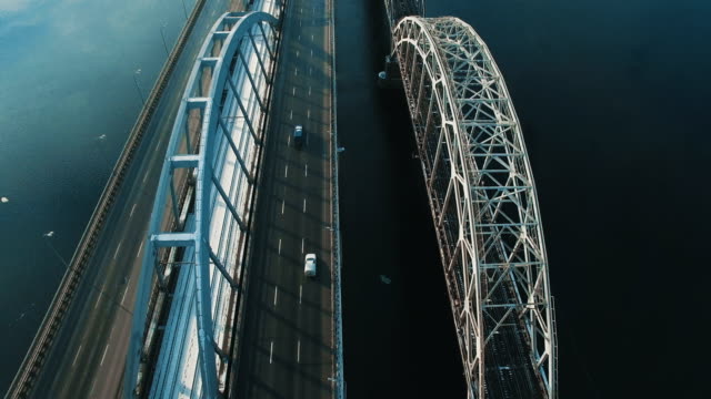 Auto-und-Zug-bewegt-sich-auf-einer-Brücke-über-einen-gefrorenen-Fluss-Luftbild-Drohne-Filmmaterial